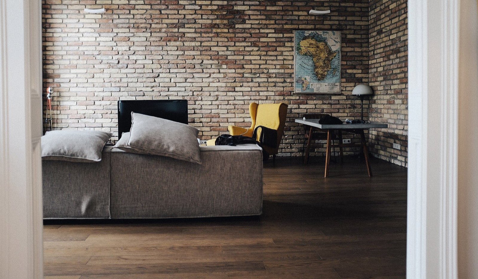 Sala cálida con pared de ladrillo, sillón amarillo y muebles de madera (foto de ambiente)